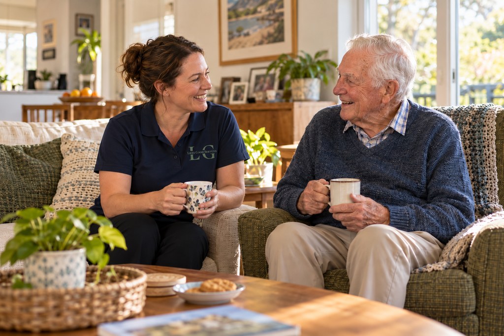 Support worker and older man sharing a relaxed conversation over tea at home